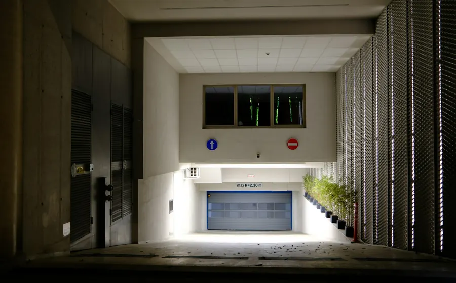 Acceso al estacionamiento de un edificio con portón de garaje iluminado