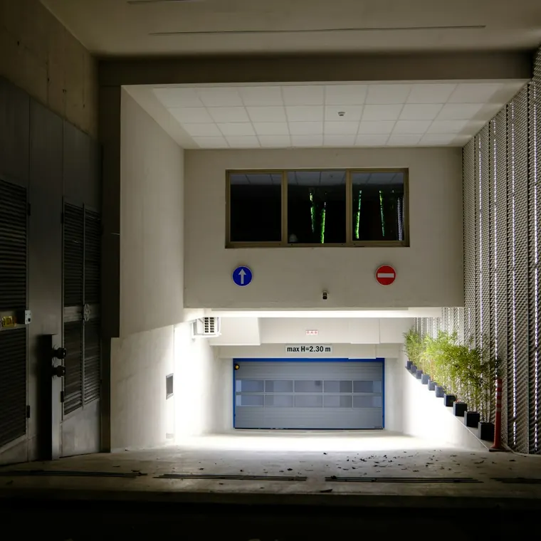 Acceso al estacionamiento de un edificio con portón de garaje iluminado