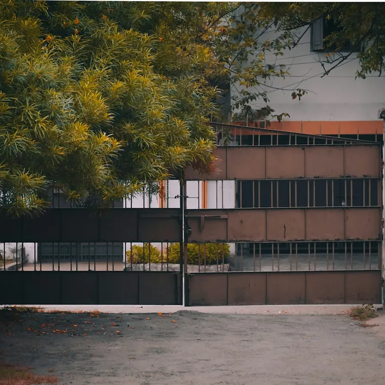 Portón corredizo oscuro de una casa con árboles detrás